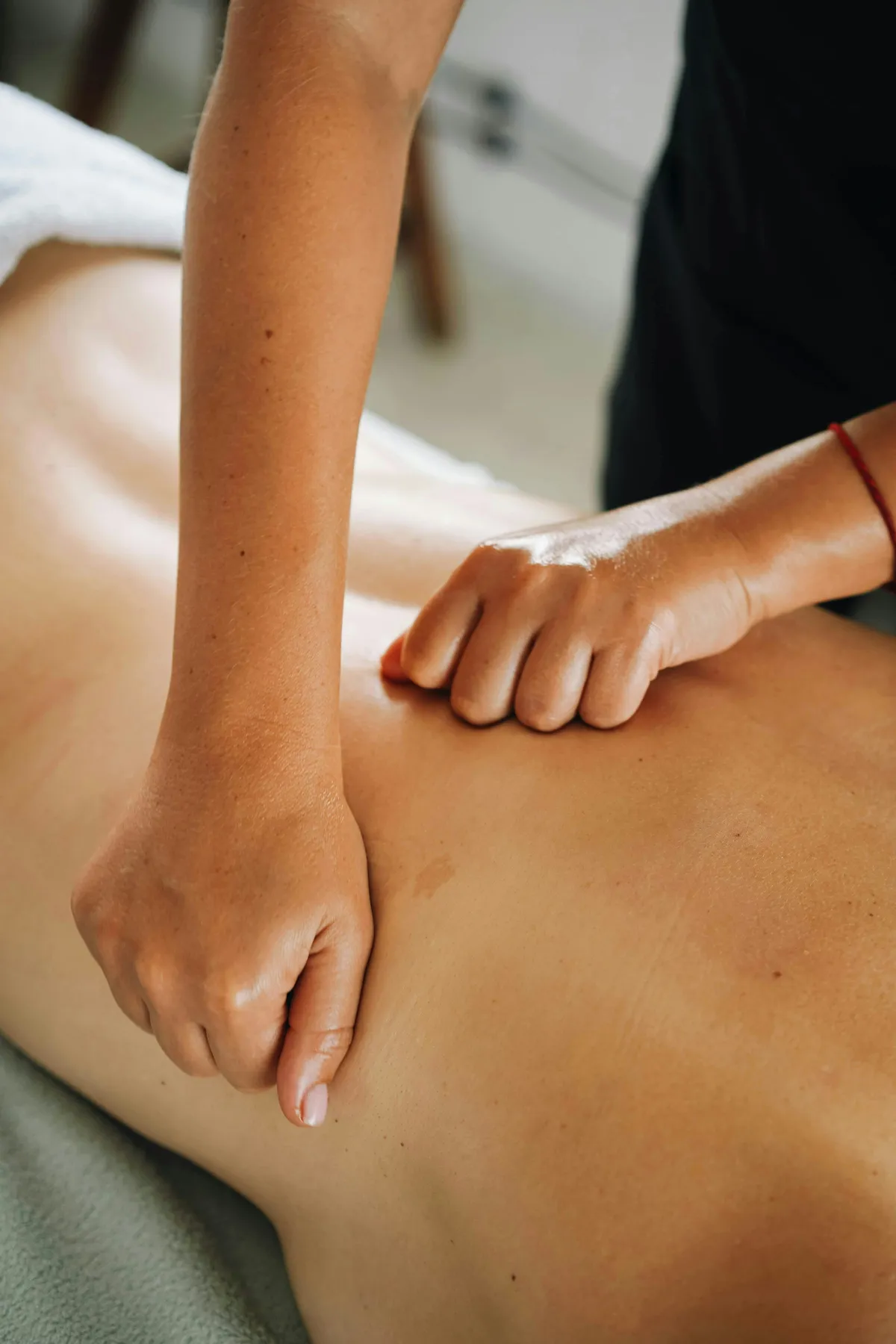 Masseuse die met stevige, gerichte druk de rugspieren masseert